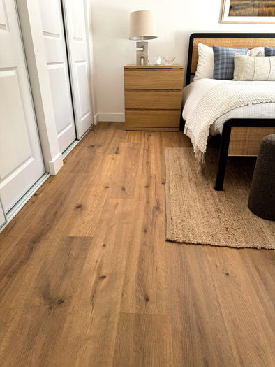 Remodeled bedroom featuring LVP flooring, sliding closet doors, and cozy modern decor with wood nightstand and textured rug