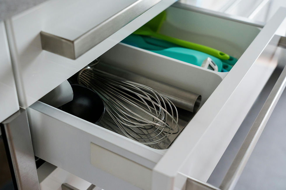 Close-up of a modern kitchen drawer with kitchen tools such as a whisk, measuring spoons, and a spatula, showcasing an organized and functional drawer layout.