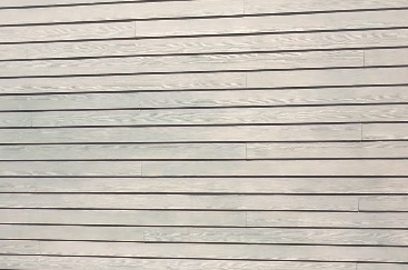 Close-up of beige horizontal siding with subtle shadows and weathered texture on a plain exterior wall