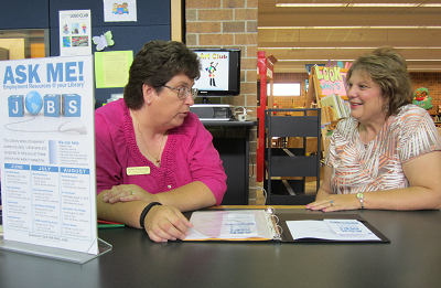 A librarian helps a person refine their job application
