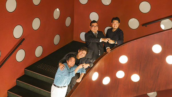 座・高円寺の螺旋階段。赤い壁に白い丸のライトが無数についた印象的な内装。踊り場で板橋さんとぱんださん、菊地さんと奥村さんがそれぞれの人差し指を交差させ、「交差」を手話で表している