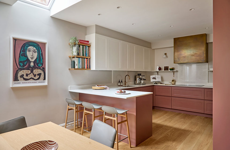 Kitchen-dining space in pink and white with burnished brass cooker hood and conteporary artwork