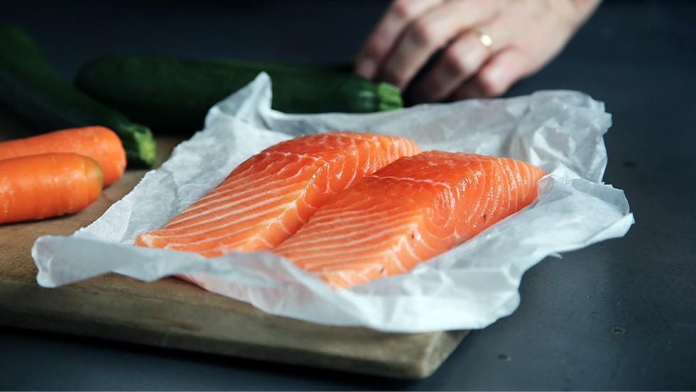 two fresh salmon filets on parchment paper ready for the oven.