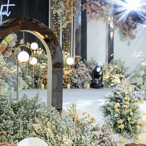 The wedding runway lined with dense green bushes, autumn-toned flowers, and modern glowing sphere lamps.