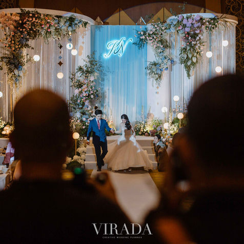 A wide view of the wedding ceremony stage featuring a soft sky-blue backdrop and glowing globe lights.