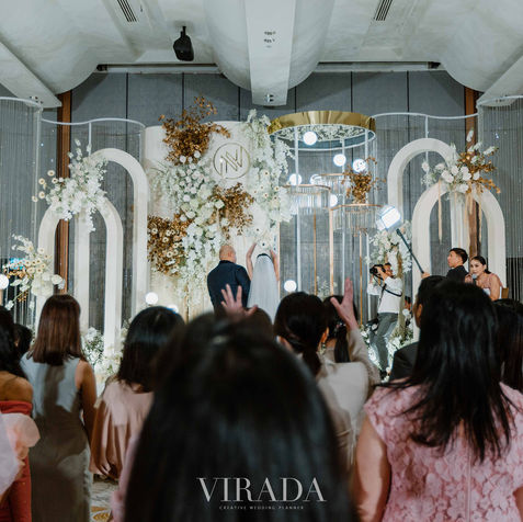 Guests entering the wedding ballroom through a massive white floral and gold archway.