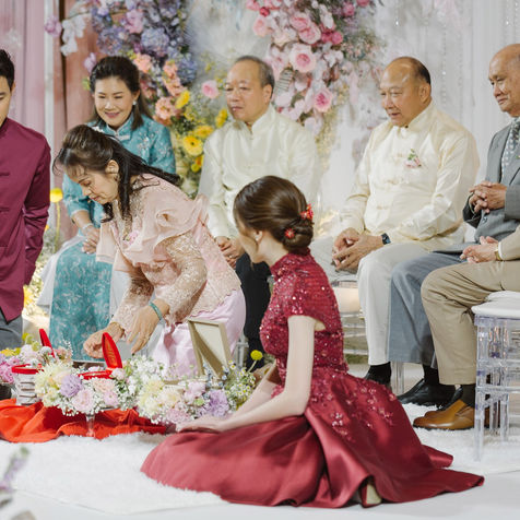 The bride in a red gown performing a traditional blessing ritual with family members.