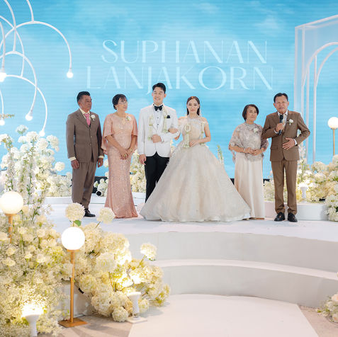 The bride, groom, and their family members standing together on an illuminated, wide multi-tiered stage.