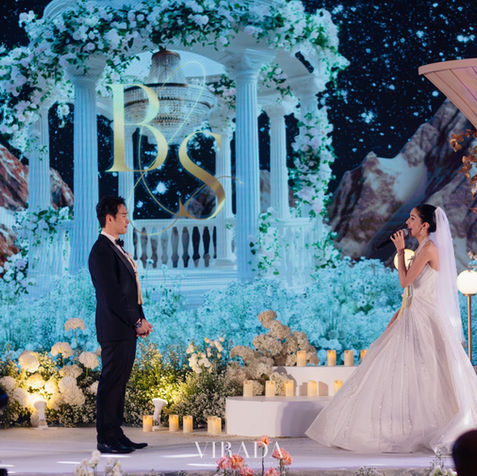 A sweet candid moment where the groom stands looking lovingly at his bride on the main wedding stage.