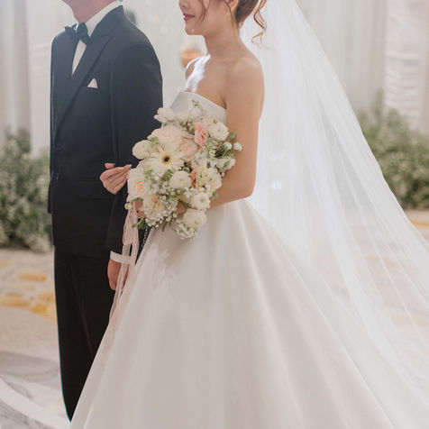 Close-up of the bride in her strapless gown holding a beautiful bouquet of white roses and lilies.
