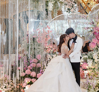 Bride and groom posing at a glamorous wedding entrance decorated with crystal bead curtains, pastel flowers