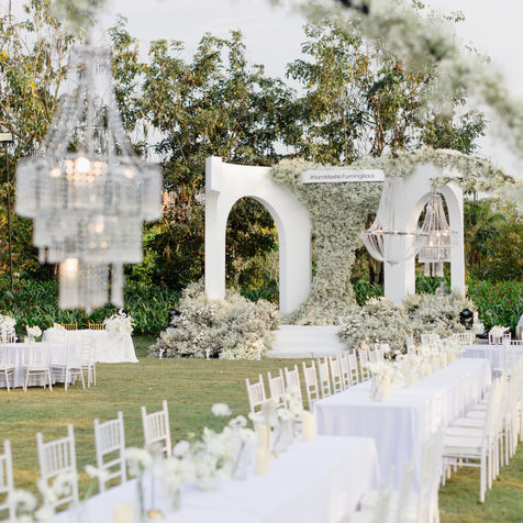 Modern garden wedding ceremony in Chiang Mai with sculptural white arch design by VIRADA