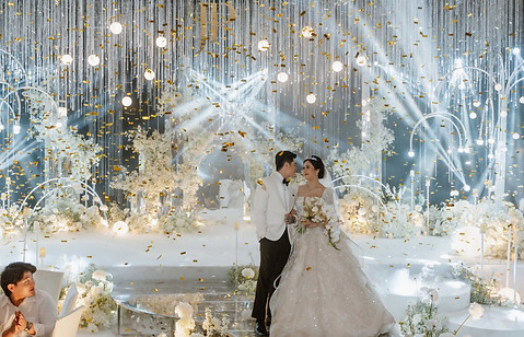Bride and groom standing on a luxury hotel wedding stage with floral backdrop and grand staircase in Chiang Mai.