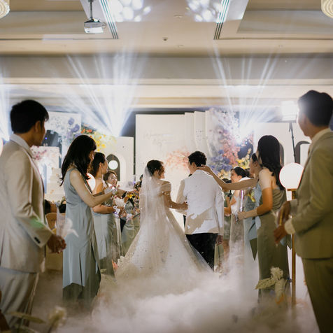 The bride and groom walking hand-in-hand while guests celebrate their union.