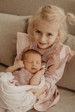 Blondes Mädchen hält ihre kleine Schwester im Arm