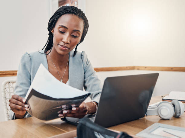 A woman reading a paper report in front of her computer
