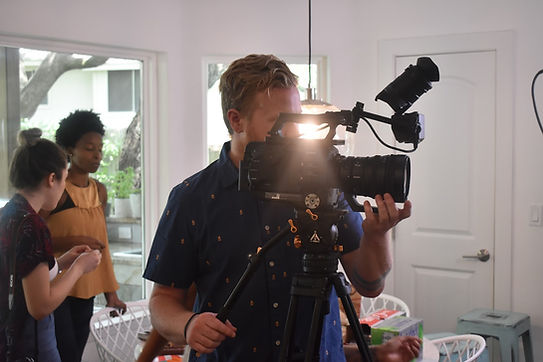 Behind-the-scenes video production with creative team using professional camera equipment in studio.
