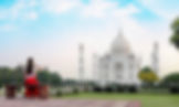 Woman in red skirt sits on a bench, admiring the Taj Mahal. Clear blue sky and lush greenery enhance the serene atmosphere. Matjaz Intihar. Fotopotep Indija.