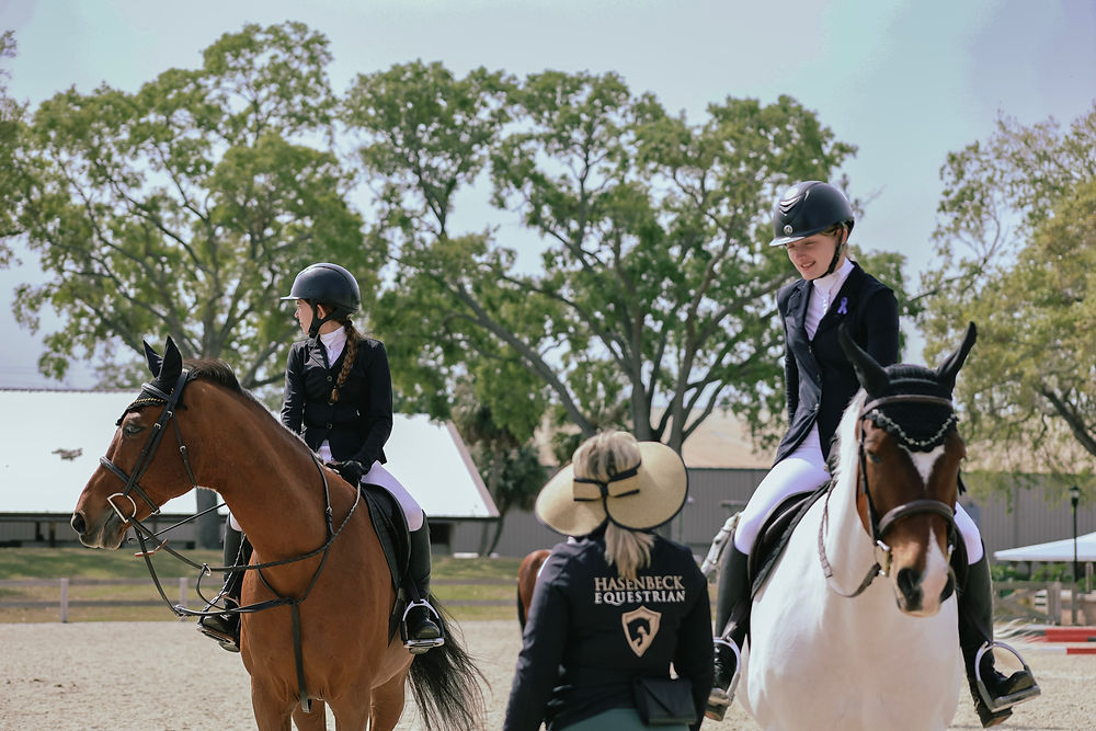 Two riders on horses with an instructor