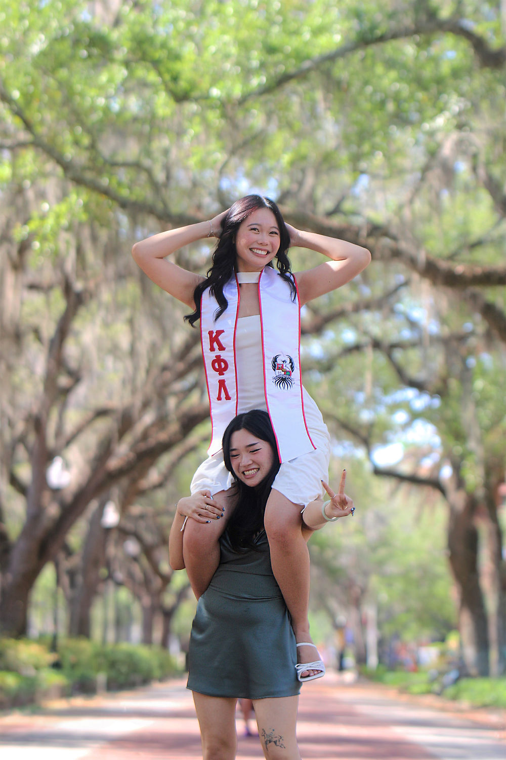 A graduate riding on her friend's shoulders