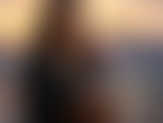 An African American woman journaling with a cityscape background at sunset