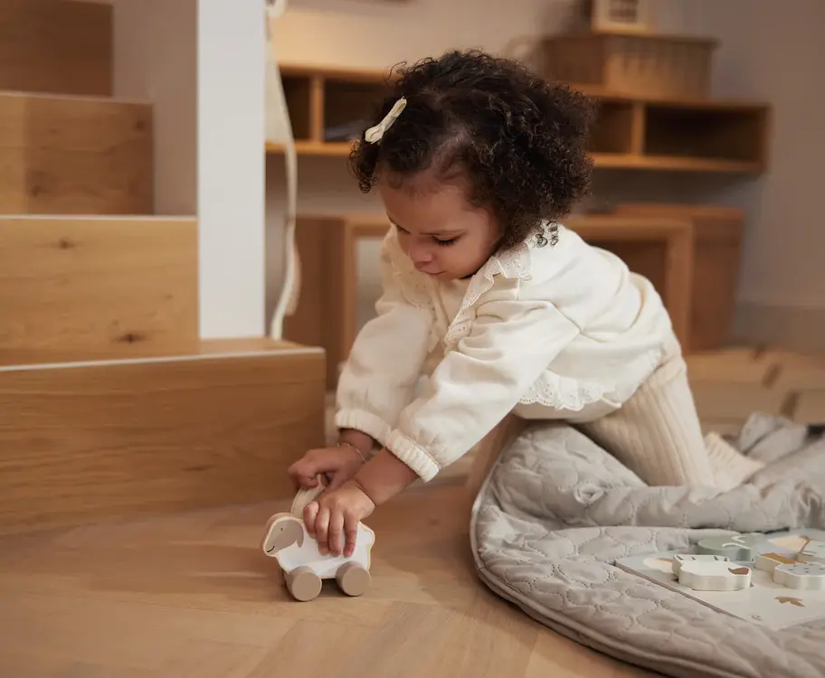 Baby spielt mit dem nachhaltigen Holzspielzeug Auto Farm Lämmchen