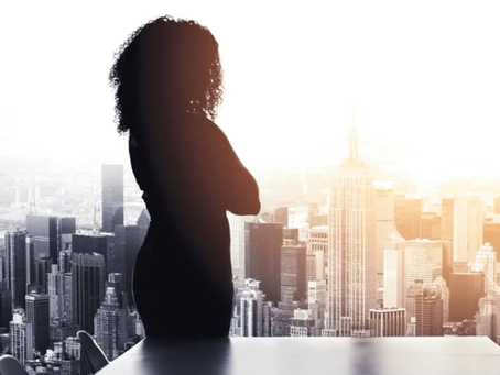 Woman in corporate office overlooking city, two woman speaking and laughing relaxed
