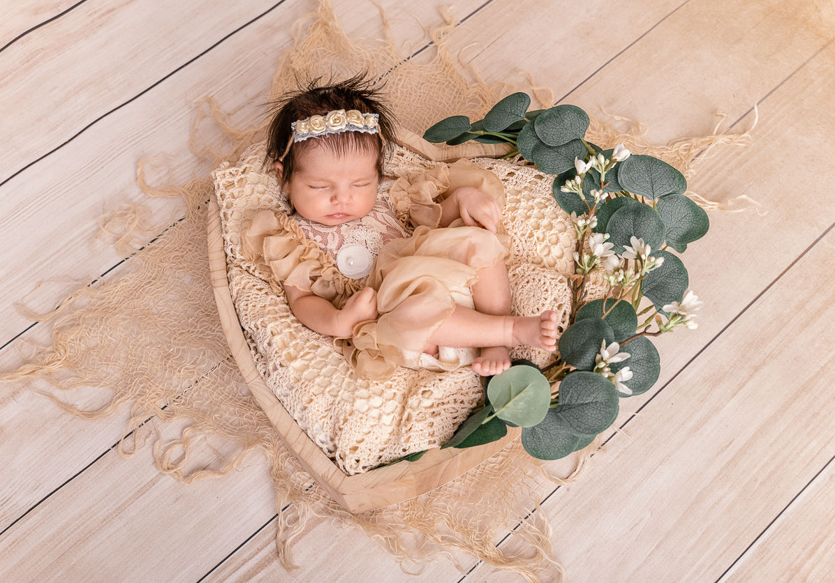 Neugeborenes Mädchen Baby in Creme tönen Angezogen liegend in einer Herzschale aus Holz