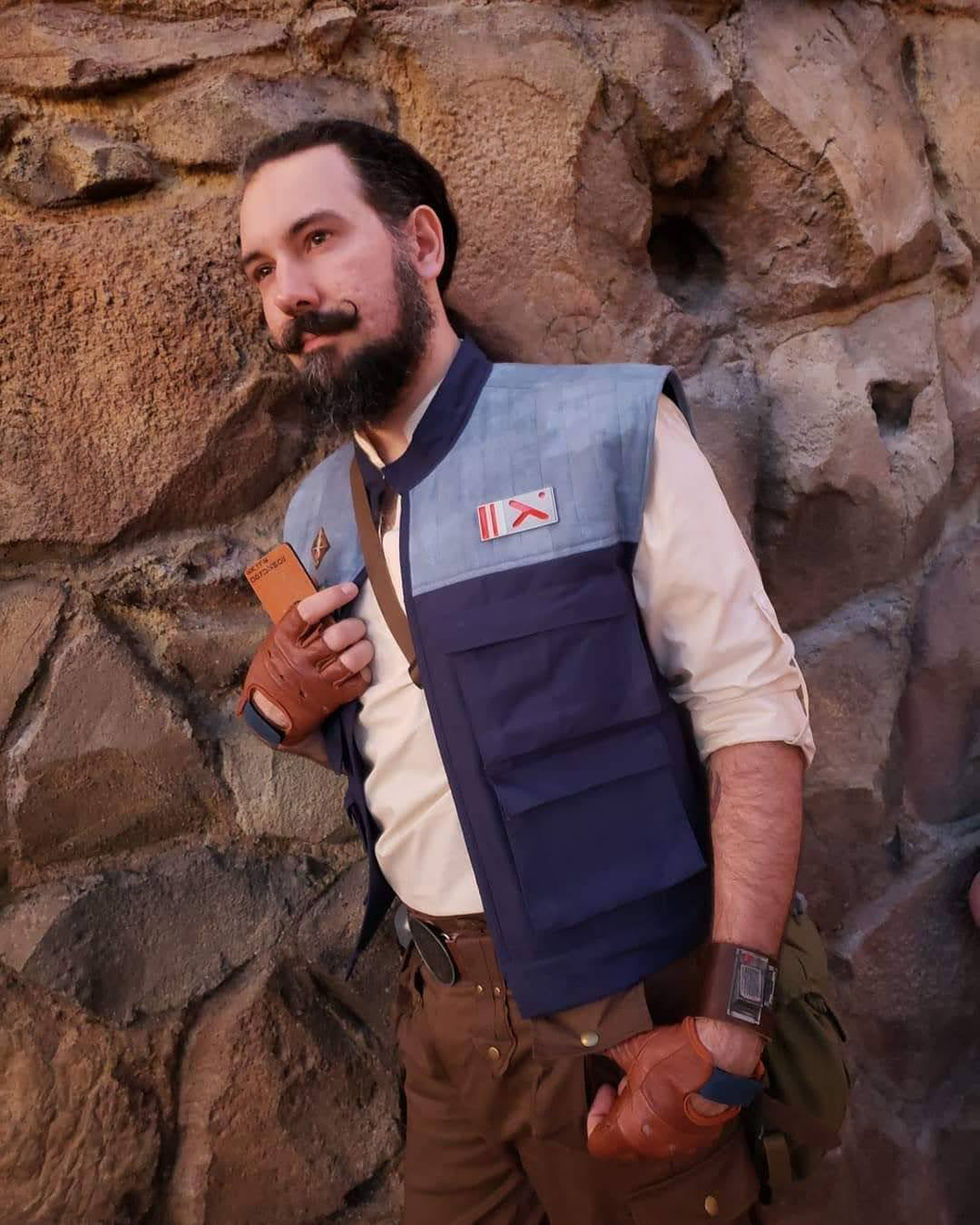 Man wearing costume leans against rocks, holding object 