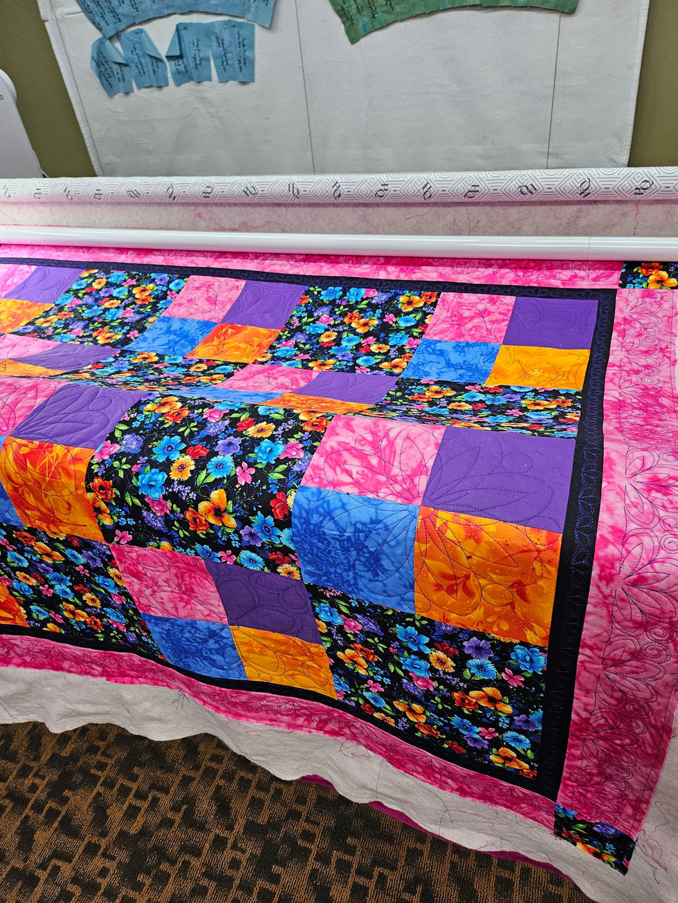 Colorful quilt with floral and patchwork design in a sewing studio.
