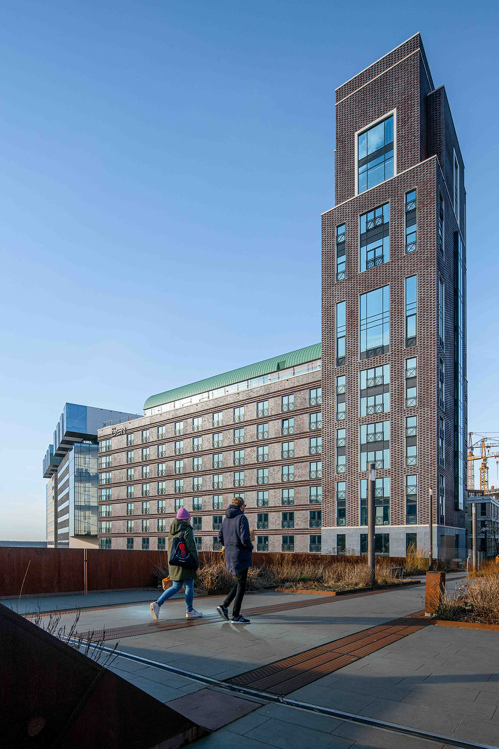 Modern hoogbouw, twee mensen lopen voorbij.