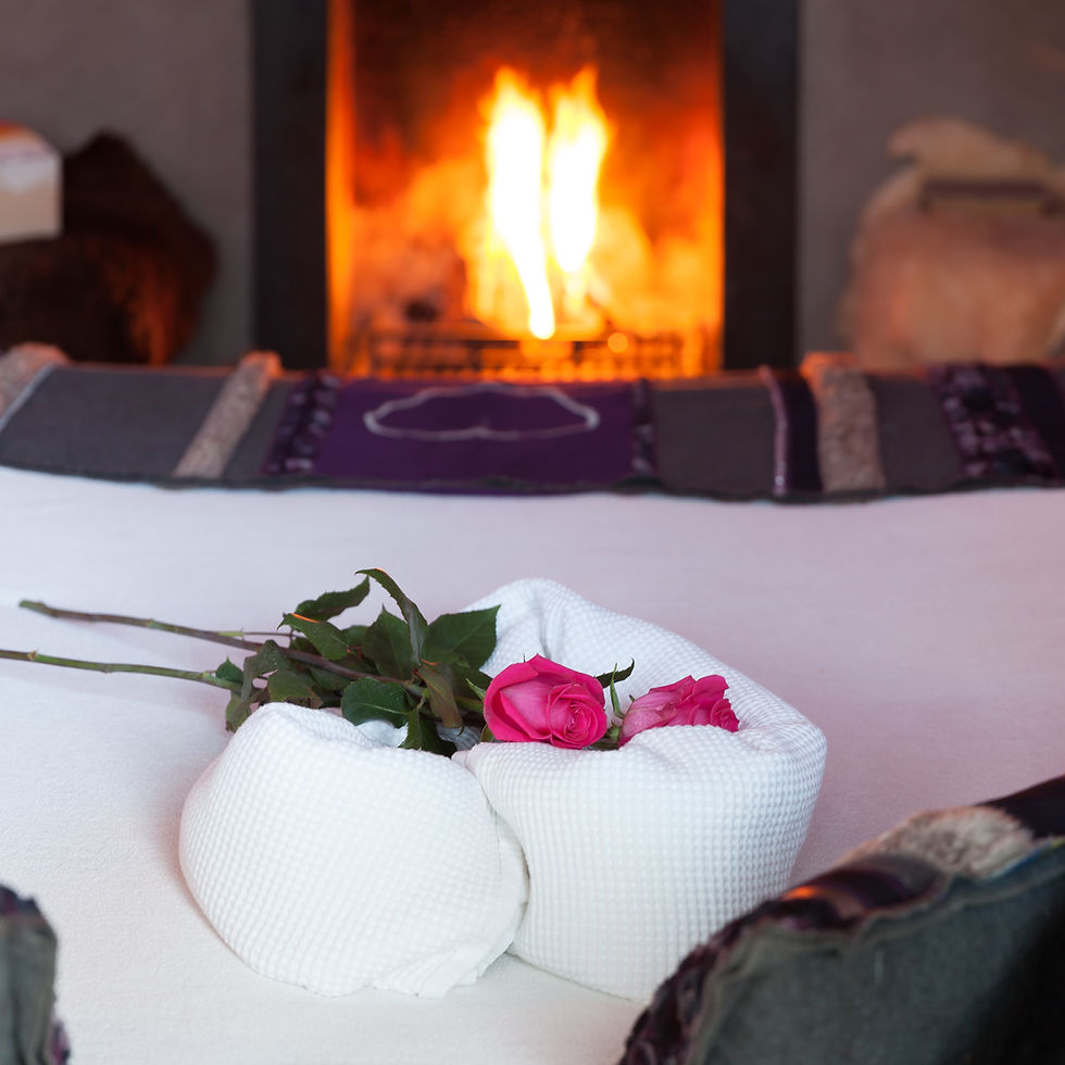 Close-up van rozen en handdoeken op een bed met brandend haardvuur op de achtergrond