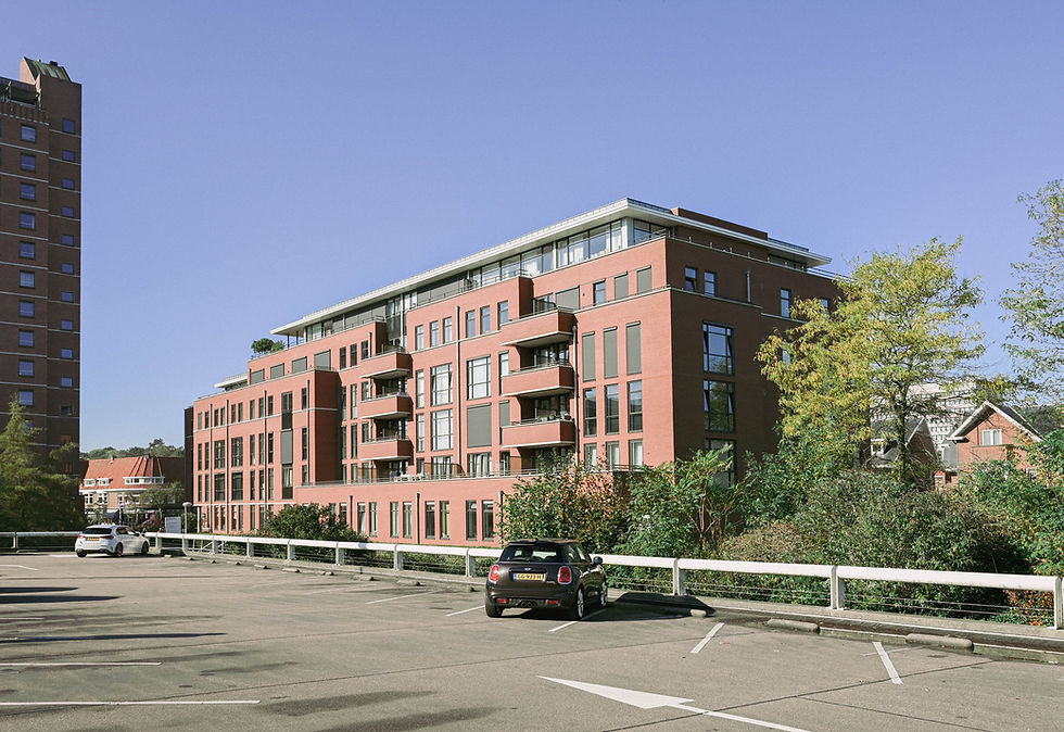 Modern rood bakstenen appartementencomplex bij een parkeerplaats.