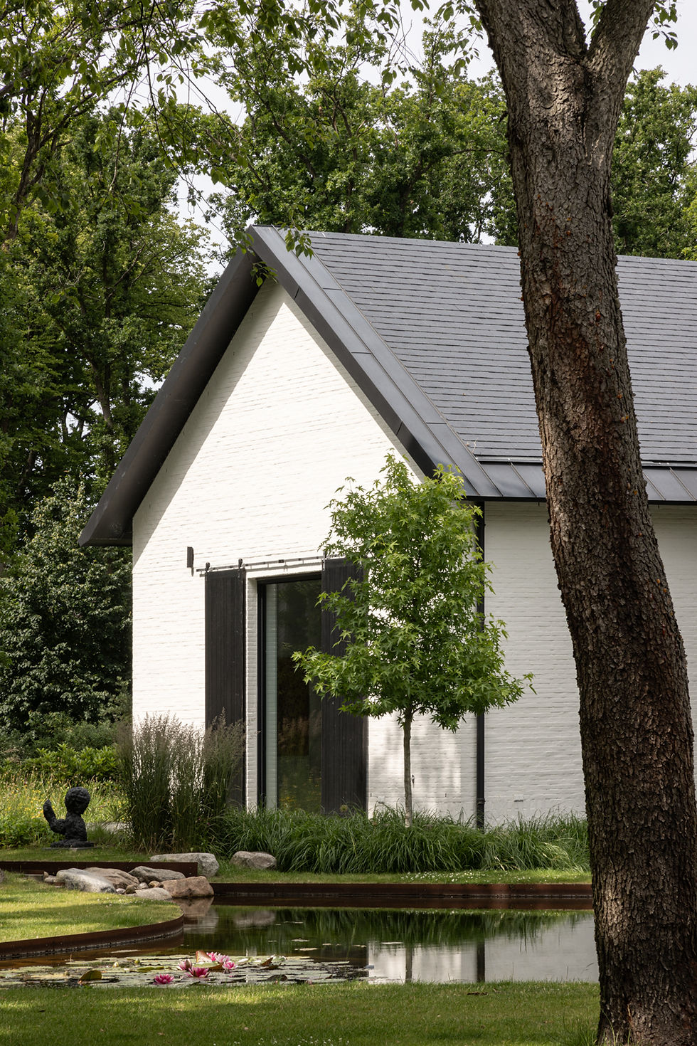 Witte schuurwoning met vijver en groene tuin