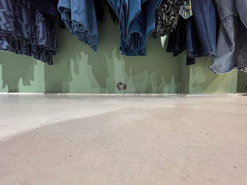 Vloer met hangende kleding en een gat in de muur