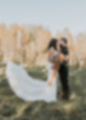 A wedding couple in a vineyard holding an orange bouquet.