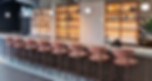 Interior of Beringers brunch restaurant featuring a stylish modern bar with pink velvet stools and backlit spirit shelves