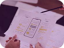 Hands holding a mobile UI design prototype on paper, discussing user interface layout and appearance.