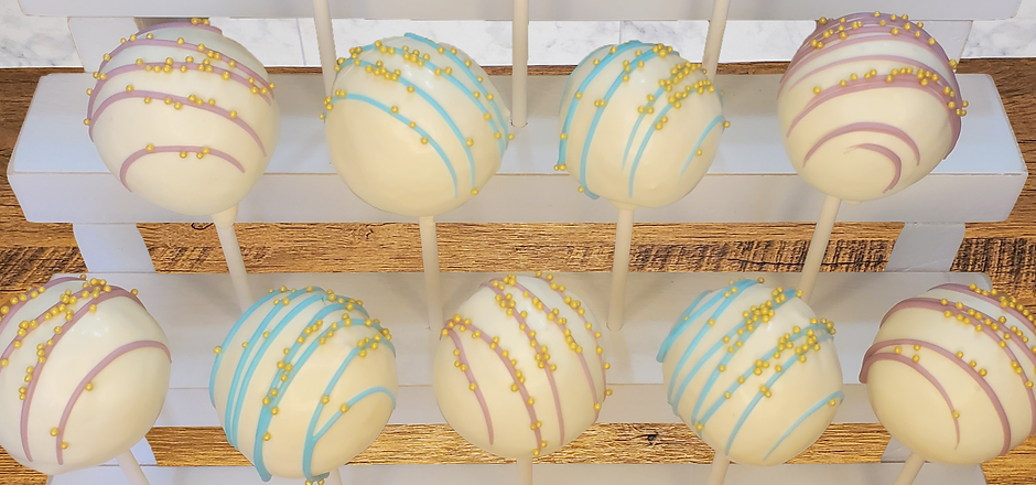 white dipped cake pops with blue and purple drizzle for baby shower