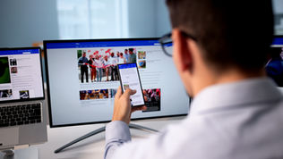 Man using a smartphone, laptop, and monitor to view pages on a screen. All for recognizing your website needs to checked on all devices.