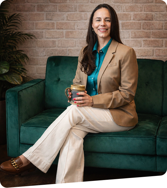 Sarah sitting on a green sofa holding a mug.