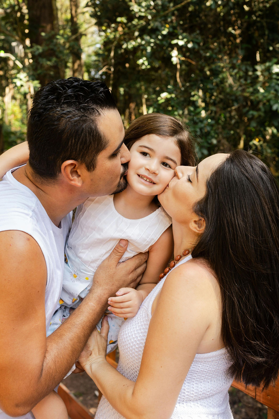 Latino parents kissing smiling daughter outdoors, representing Latino mental health support in Western Massachusetts