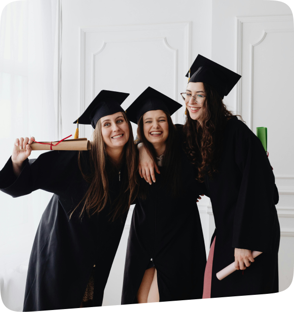 Three smiling graduates in caps and gowns holding diplomas