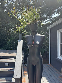 Black mannequin with a plant for a head named Lakshmi