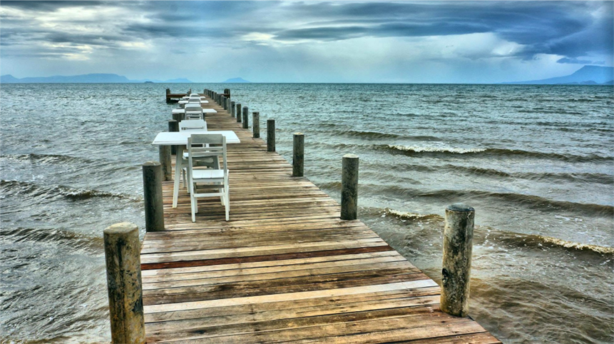 The property's wooden pier stretches far out into the water, lined with white tables and chairs, under a cloud-heavy sky. (Archive photo)