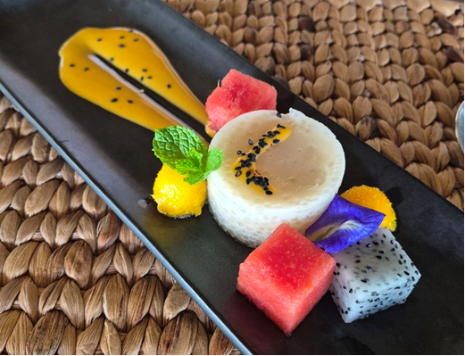 A coconut dessert with tropical fruit and butterfly-pea flowers