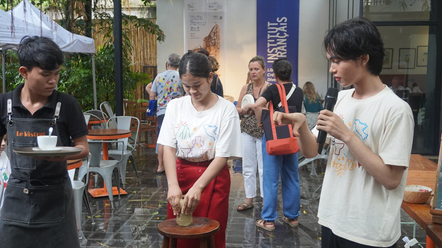 A live pottery demonstration, microphone in hand, in front of forum visitors