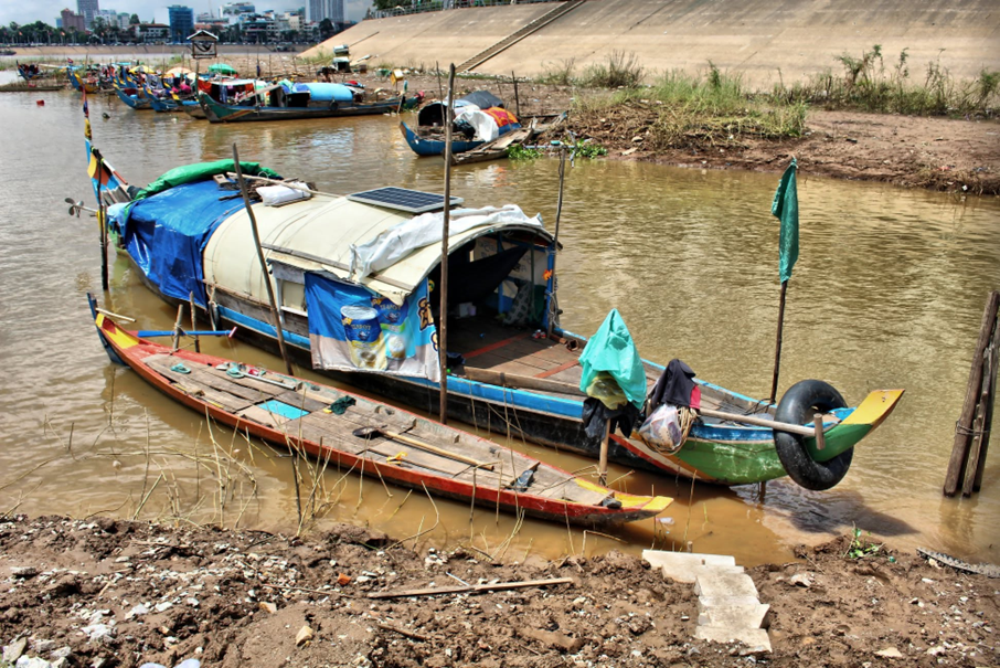 Un panneau solaire installé à même le toit de bâche d'une barque témoigne de l'ingéniosité déployée pour vivre à bord sur le long terme, boîte de lait concentré séchant sur la corde à linge