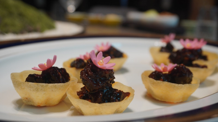 Crisp pastry cups filled with caramelised morsels, each topped with a pink sugar flower