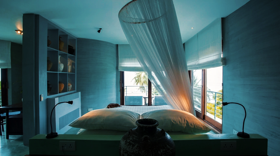 Une chambre baignée de bleu profond, moustiquaire suspendue et vue directe sur la mer